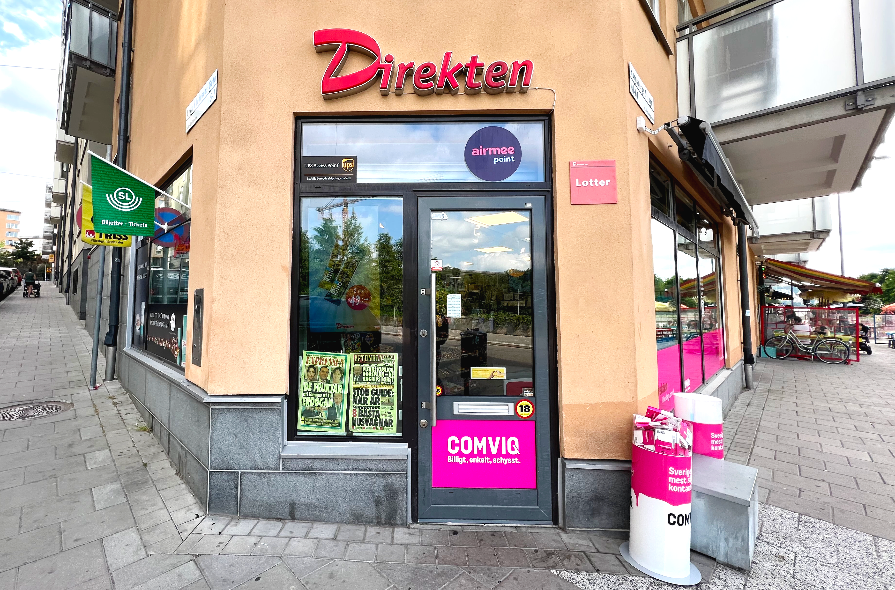 Butiksentré till Direkten på gatuhörn i beige hus med färgglada skyltar för lotter, Comviq och SL.
