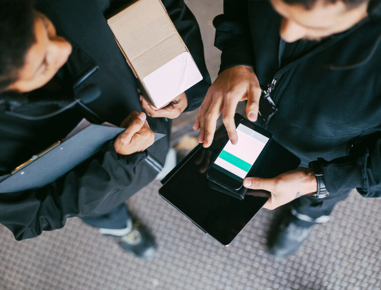 Närbild på två personer i arbete där en använder mobil för orderhantering i integrationssystem med Cash-IT kassasystem och den andra håller ett paket.